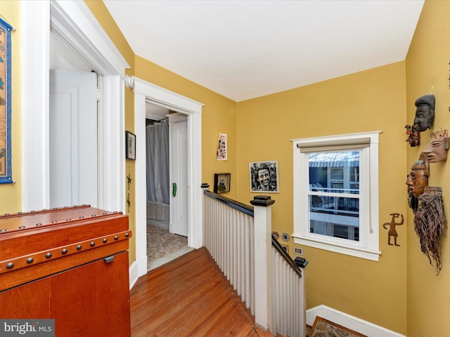 corridor with an upstairs landing and light wood-style floors