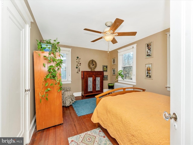 bedroom featuring a ceiling fan, radiator, wood finished floors, and baseboards