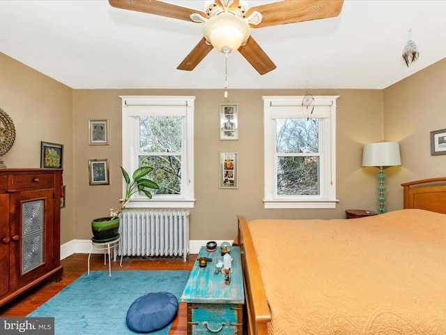 bedroom with baseboards, multiple windows, wood finished floors, and radiator heating unit