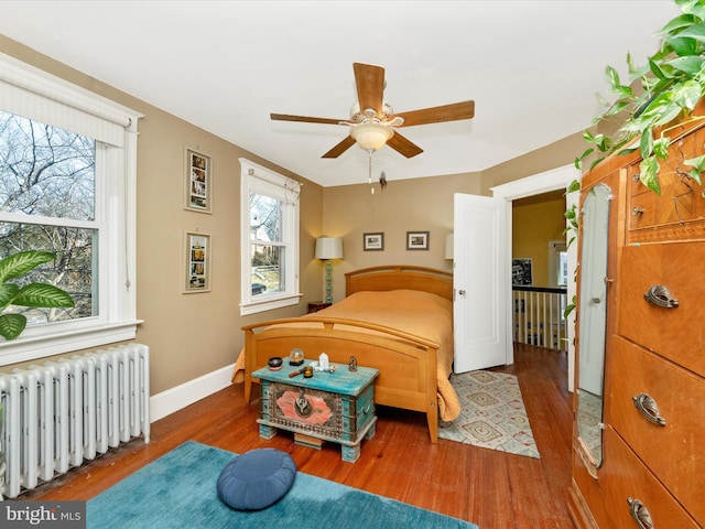 bedroom with radiator, wood finished floors, baseboards, and ceiling fan