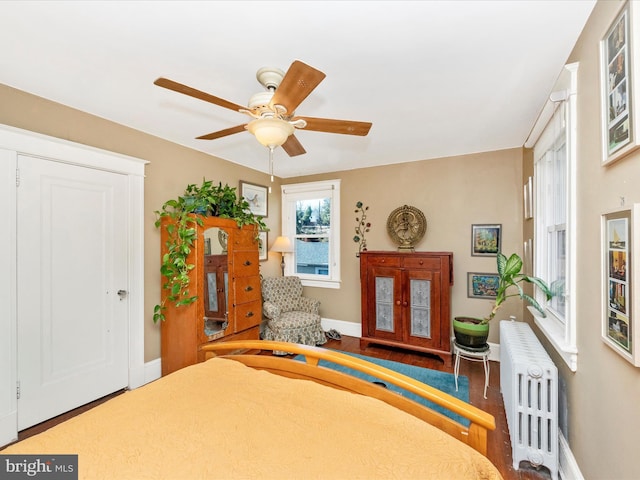 bedroom featuring wood finished floors, baseboards, ceiling fan, and radiator heating unit