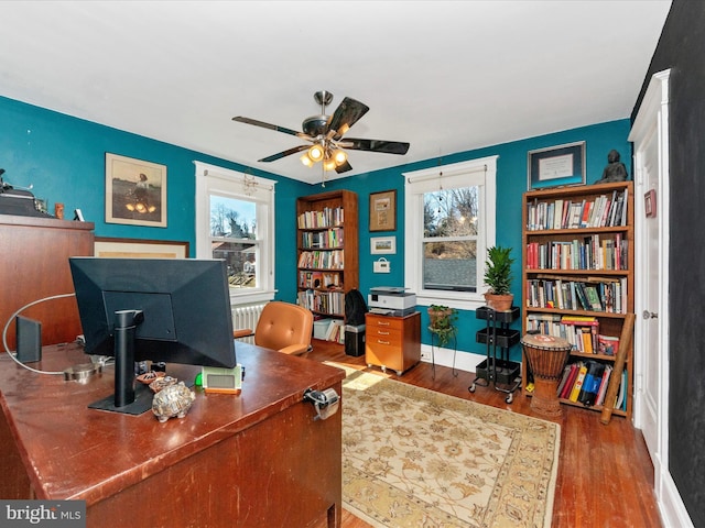 office area with a ceiling fan, wood finished floors, baseboards, and a healthy amount of sunlight