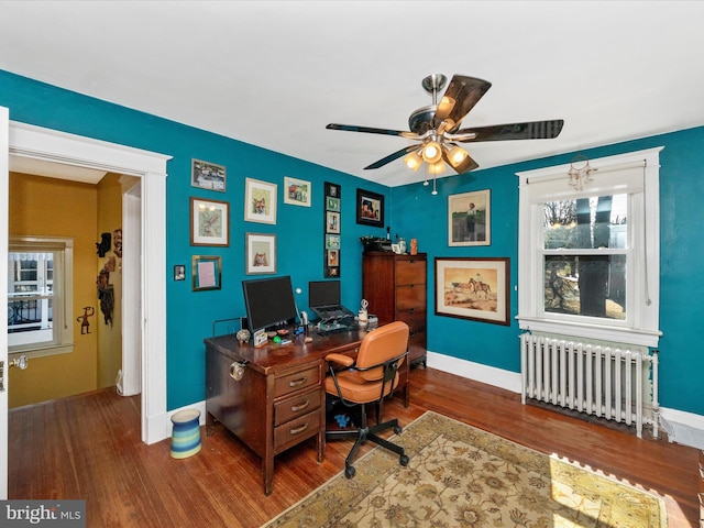 home office with radiator heating unit, baseboards, and wood finished floors