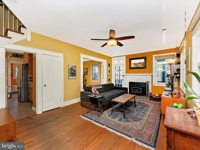 living room with a fireplace, baseboards, a ceiling fan, and wood finished floors