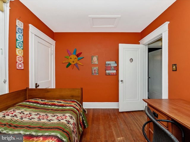 bedroom with baseboards, attic access, and wood finished floors