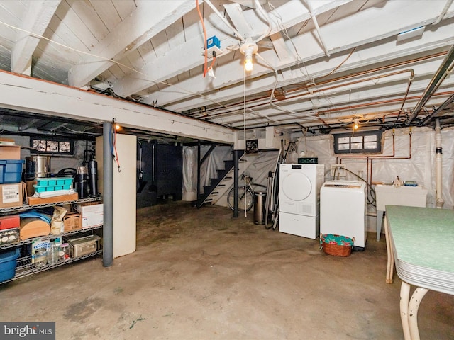 unfinished basement with a sink, stairway, and washing machine and clothes dryer