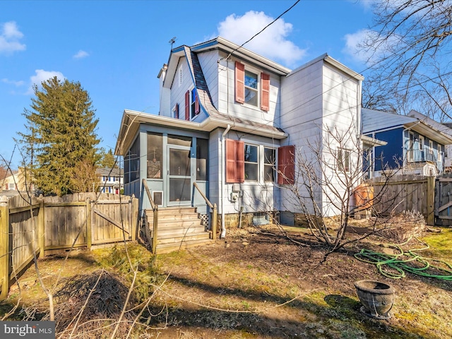 view of front of house with fence, a gambrel roof, entry steps, a sunroom, and a gate