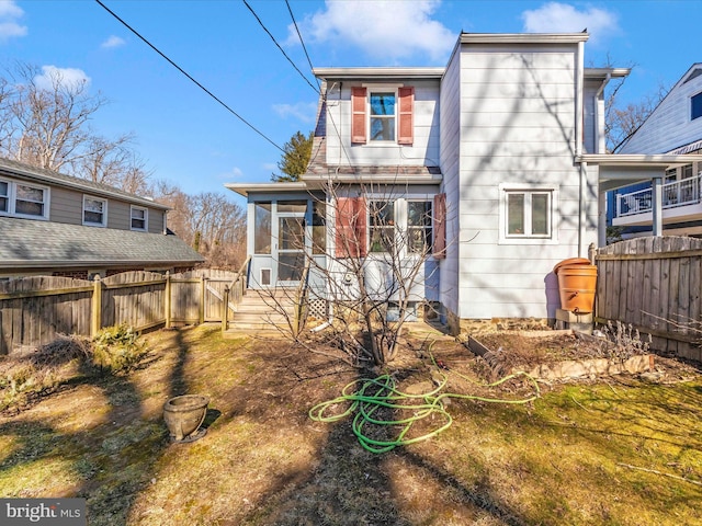 rear view of house with fence and a sunroom