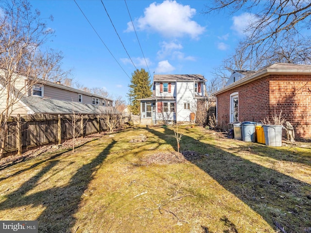 rear view of house with a yard, fence, and brick siding