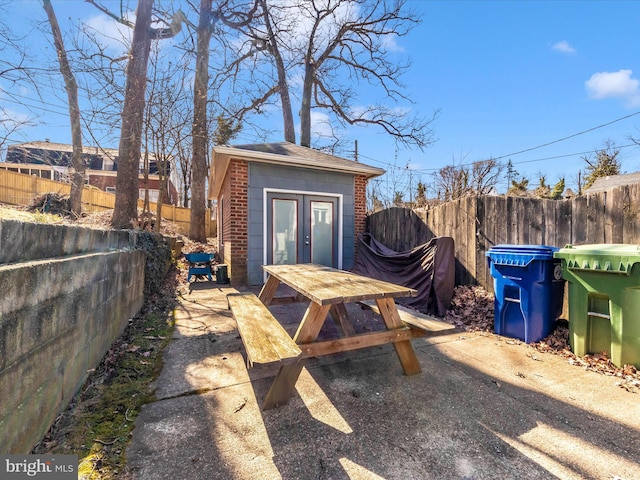 view of outdoor structure with outdoor dining space, an outdoor structure, and a fenced backyard