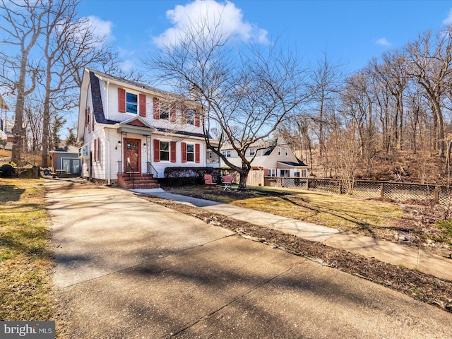 view of front of house featuring a fenced front yard, a chimney, an outdoor structure, and driveway