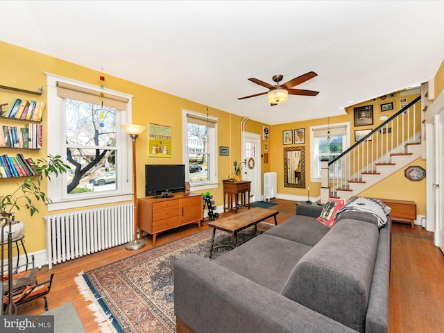 living area featuring stairs, radiator heating unit, and a wealth of natural light