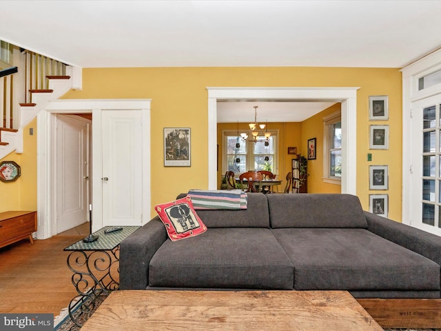 living room with stairway, a notable chandelier, and wood finished floors