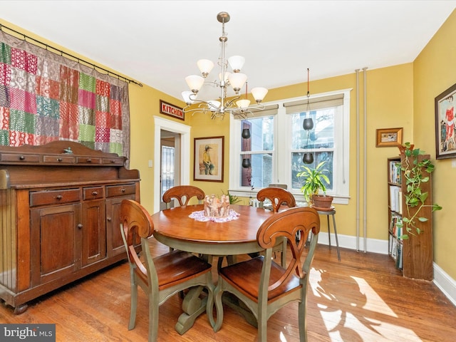 dining space with light wood-type flooring, baseboards, and a notable chandelier