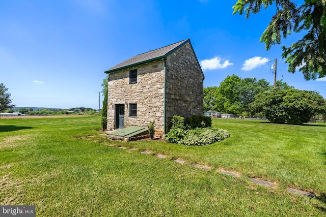 view of side of property featuring stone siding, a yard, and fence