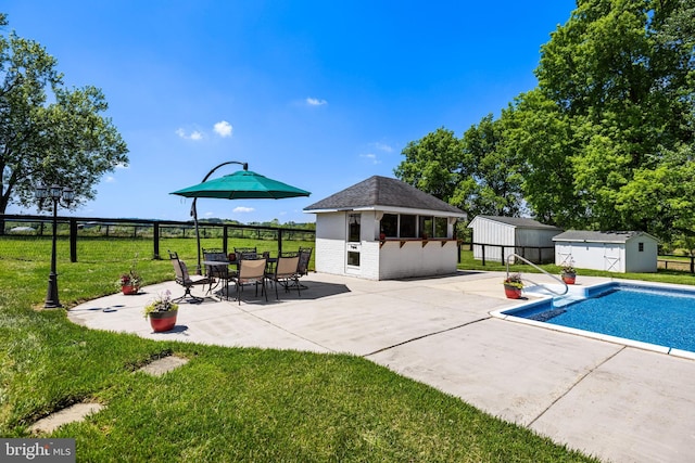 view of swimming pool with a lawn, a patio, an outdoor structure, and fence