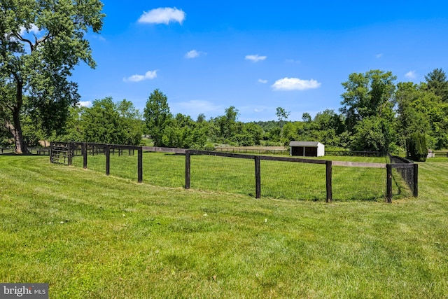 view of yard featuring a rural view, an outbuilding, and fence