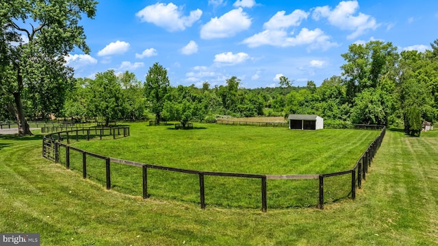 view of yard featuring a rural view, an outdoor structure, and fence