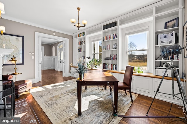 office with crown molding, built in shelves, dark wood-style flooring, and a chandelier