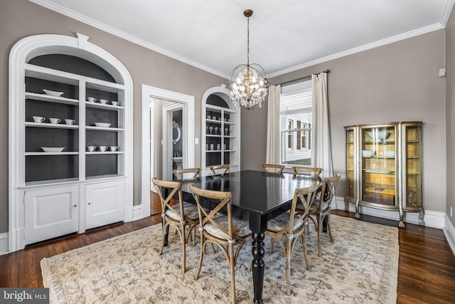 dining room with built in features, a notable chandelier, dark wood-style floors, and ornamental molding