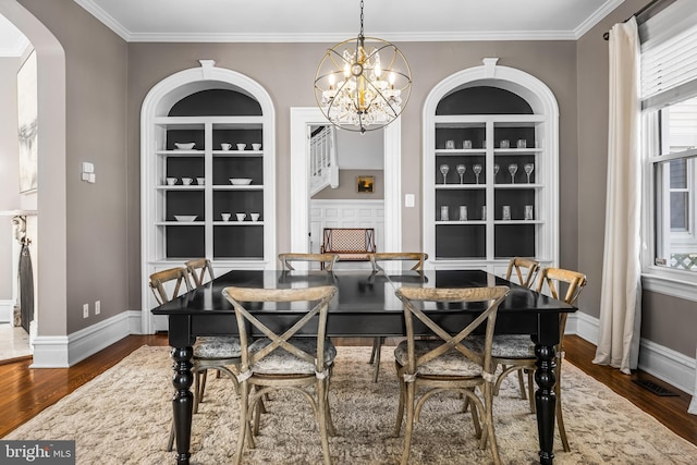 dining space featuring arched walkways, dark wood-style floors, and built in shelves