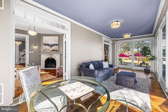 living area featuring baseboards, a fireplace with flush hearth, stairs, ornamental molding, and wood finished floors