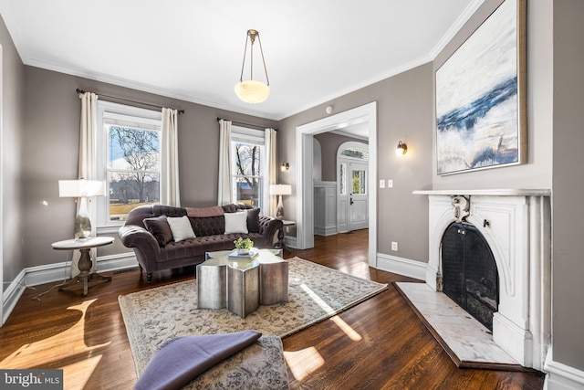 living room with a fireplace with flush hearth, crown molding, baseboards, and wood finished floors