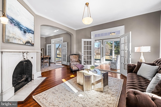 living area featuring french doors, arched walkways, dark wood-type flooring, and a fireplace with flush hearth