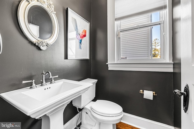 bathroom featuring a sink, baseboards, and toilet