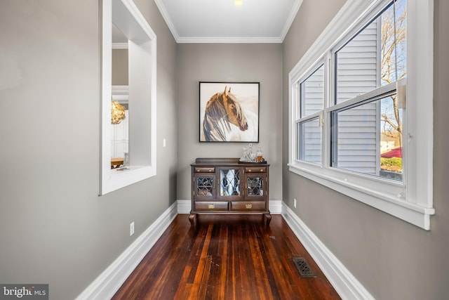 hallway featuring hardwood / wood-style floors, crown molding, baseboards, and visible vents