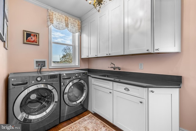 laundry area featuring cabinet space, washer and dryer, wood finished floors, and a sink