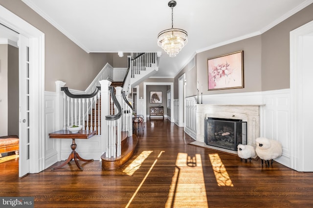 foyer entrance with stairway, wood finished floors, a high end fireplace, and ornamental molding