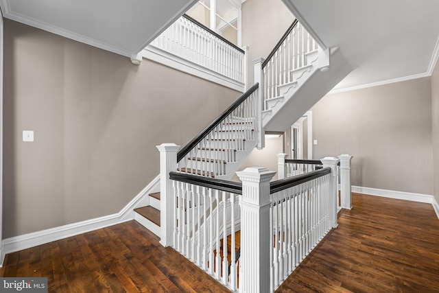 stairway with hardwood / wood-style floors, crown molding, baseboards, and a towering ceiling