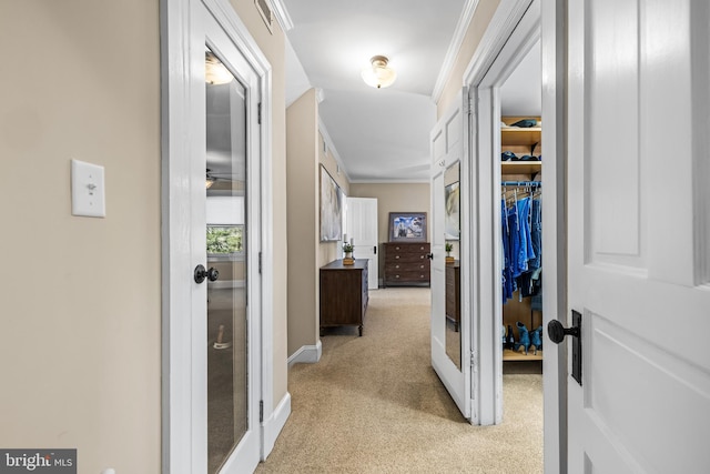 hall with light colored carpet, french doors, baseboards, and ornamental molding