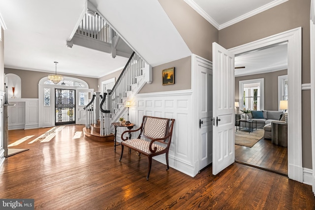 entryway featuring a wainscoted wall, stairs, ornamental molding, a decorative wall, and wood-type flooring