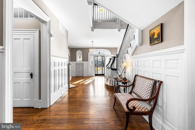 interior space with visible vents, a wainscoted wall, wood finished floors, a decorative wall, and stairs