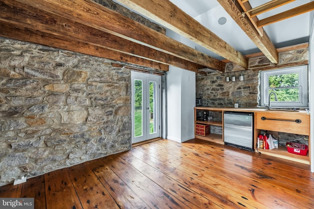 bar featuring a dry bar, plenty of natural light, stainless steel fridge, and wood-type flooring