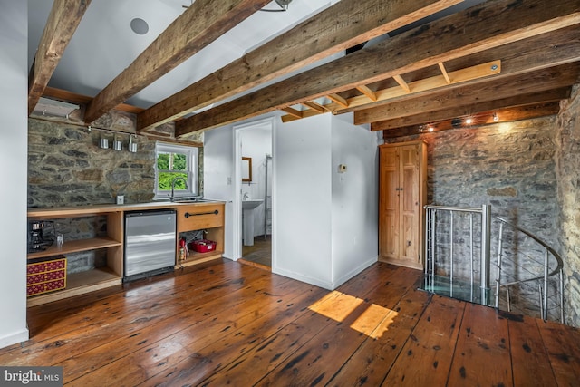 kitchen featuring beamed ceiling, stainless steel refrigerator, a sink, hardwood / wood-style floors, and baseboards