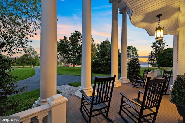 wooden deck featuring a porch and a yard