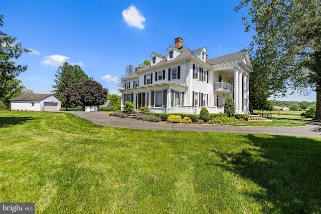 view of front of property with a front yard, a balcony, a garage, and a chimney