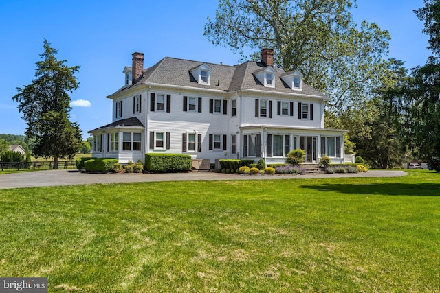 view of front of home featuring a front lawn, a chimney, and a sunroom