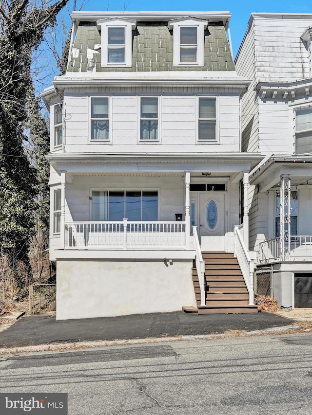 victorian home featuring mansard roof, a porch, and stairway