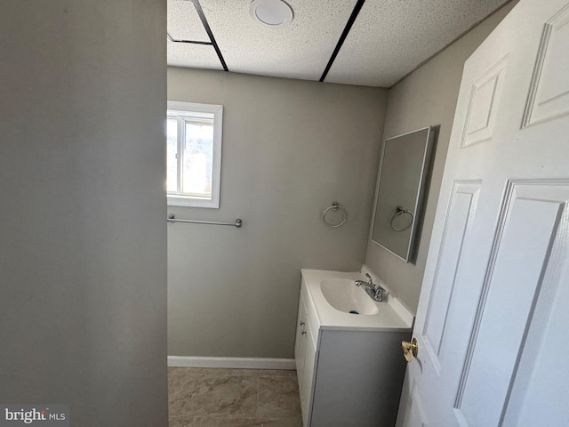 bathroom featuring a drop ceiling, baseboards, and vanity