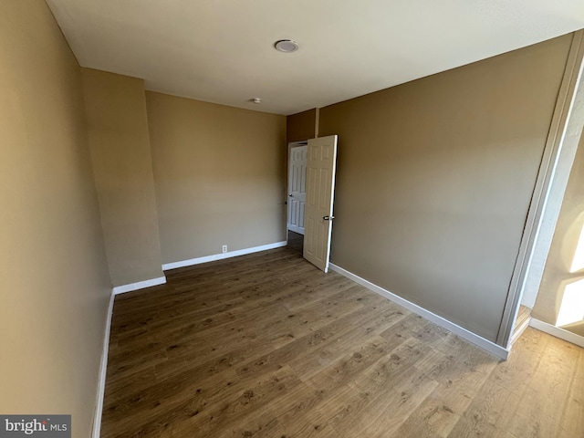 unfurnished bedroom with wood finished floors and baseboards