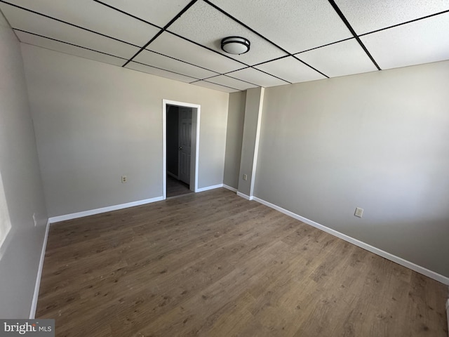 unfurnished bedroom with a drop ceiling, baseboards, and wood finished floors