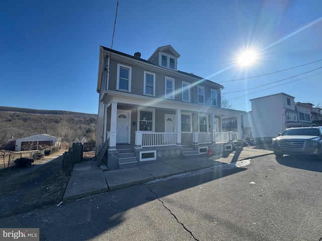 american foursquare style home with a porch and fence