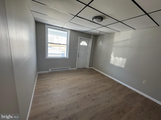 foyer with a drop ceiling, baseboard heating, baseboards, and wood finished floors