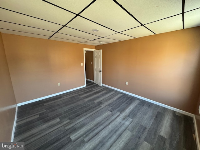 empty room with dark wood-style floors, baseboards, and a drop ceiling