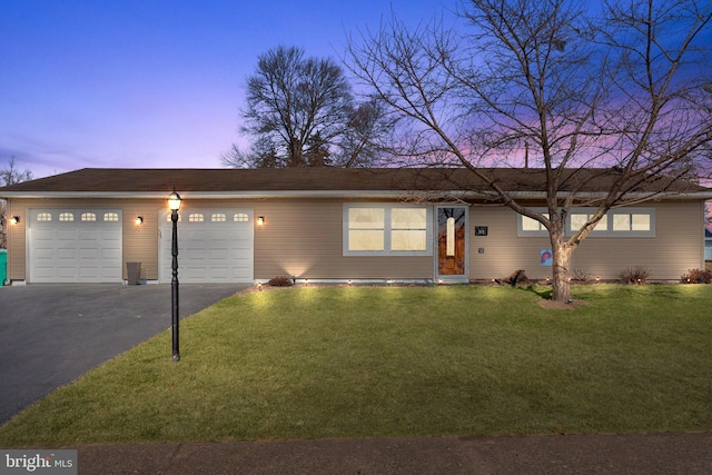 ranch-style house featuring a yard, a garage, and driveway