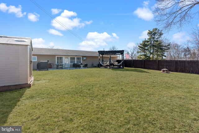 view of yard with a shed, an outdoor fire pit, a fenced backyard, an outdoor structure, and a patio area